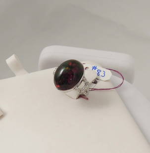 DESIGNER OSCAR FRIEDMAN LADIES PLATINUM, BLACK OPAL AND DIAMOND RING: An open work mount supports a cabochon firey black opal weighing approx. 10.66 cts. Ring completed with full cut round diamonds totaling .59 ct. Signed.