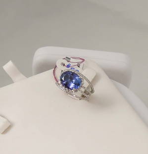 DESIGNER OSCAR FRIEDMAN LADIES PLATINUM, TANZANITE & DIAMOND RING: A modern platinum mount with three swirling rows supports an oval cut tanzanite weighing 4.30 cts. Ring completed with full cut round diamonds totaling .82 ct. Signed inside ring.