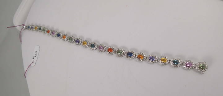 LADIES 18K W.G. & MULTI COLORED SAPPHIRE AND DIAMOND BRACELET: An eternity style bracelet with oval sections. Each section set with a different colored oval sapphire. Each sapphire surrounded by a single row of full cut round diamonds. Total sapphire weight