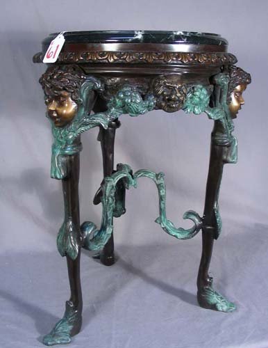 HEAVY FRENCH BRONZE TABLE WITH MARBLE TOP: HEAVY FRENCH BRONZE TABLE WITH MARBLE TOP Tri-footed bronze table with busts of children and lions supports a double tiered black marble base. Very fine detail. Three color patina. 28" high, 21" dia.
