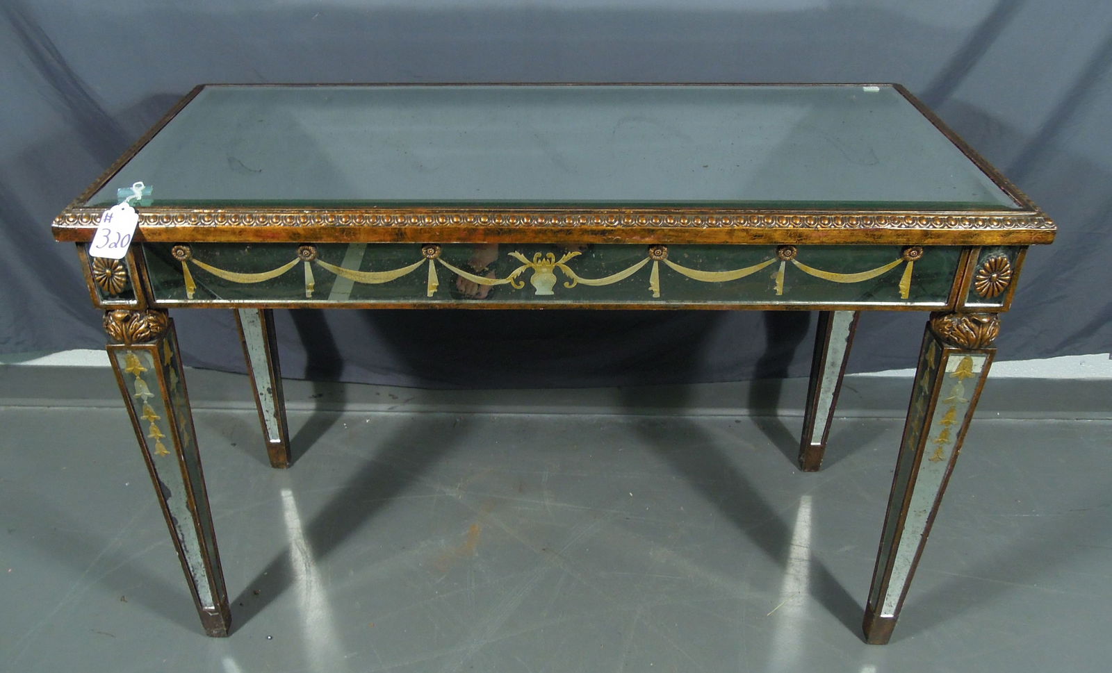 VINTAGE CARVED AND REVERSE PAINTED MIRRORED CONSOLE TABLE: Ornate carved with beveled glass top. 30" high, 44 3/4" wide, 20" deep. Note: Inside back leg has small crack in glass.