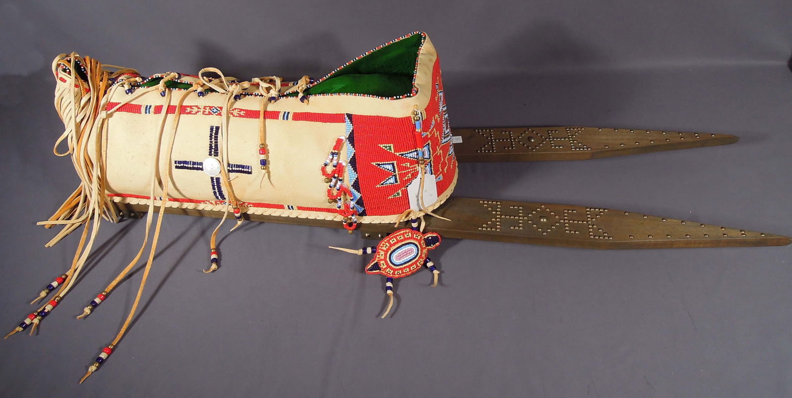 HAND MADE NATIVE AMERICAN CHILD'S CRADDLE BOARD: Leather craddle heavily beaded with Native American design. Signed K.D. Fast Horse. 10" high, 42" long, 9" wide.