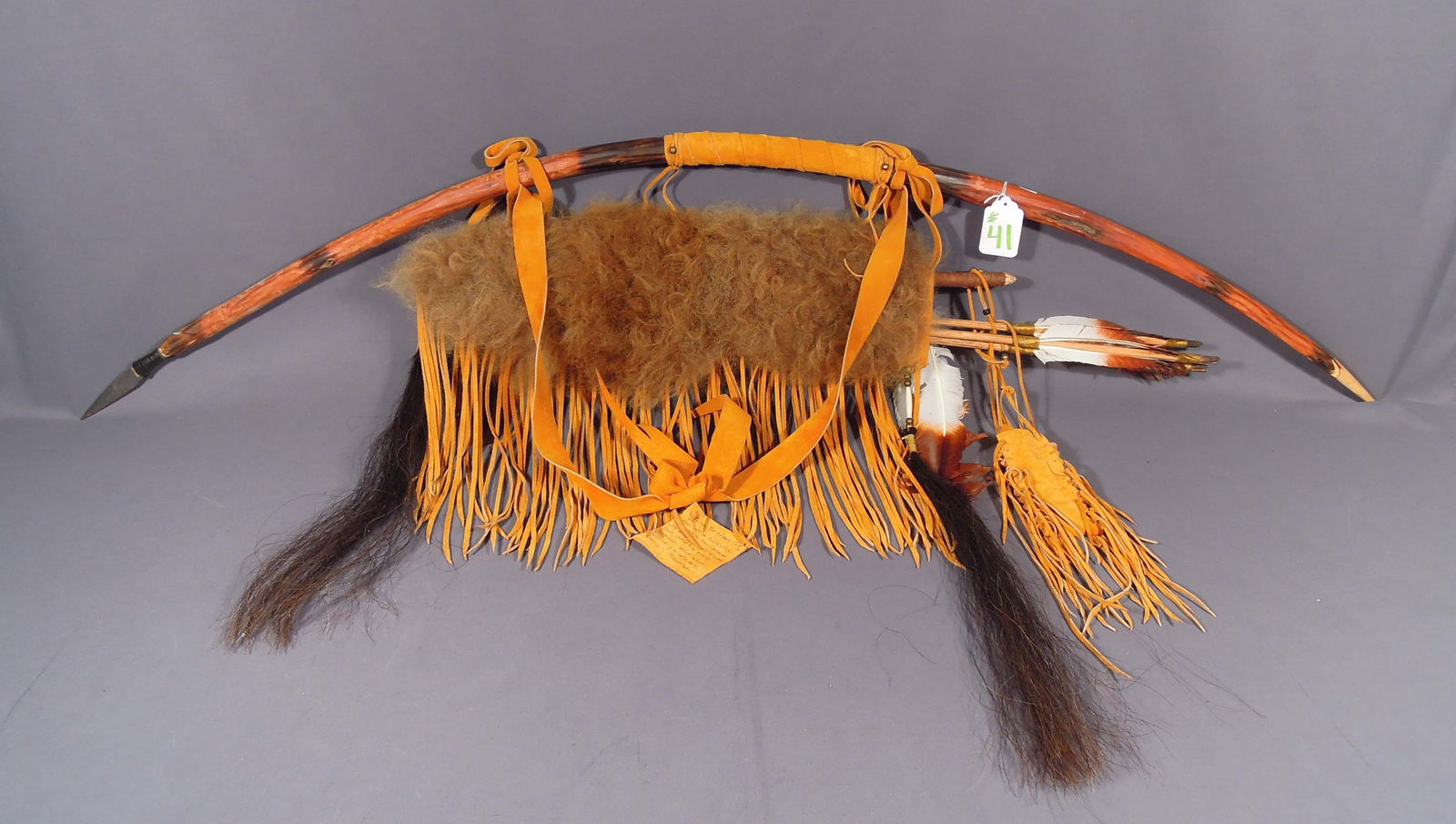 NATIVE AMERICAN BUFFALO HIDE BOW & ARROW SET: Made with a buffalo hide quiver. Willow bow debraided with brass glass and hair bone beads. Indian head nickle. Horse hair and eagle feathers. Signed. 5' long,
