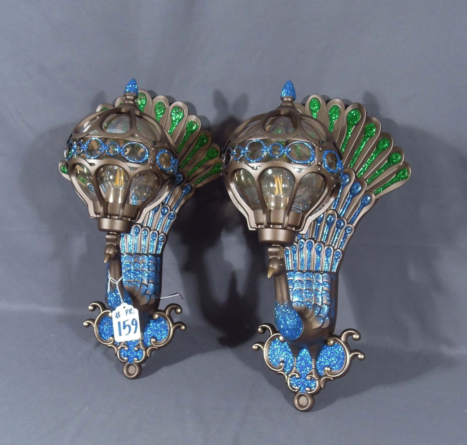 PAIR OF DECORATIVE PEACOCK MOTIF PLASTIC, GLITTER & GLASS WALL SCONCES: Colorful peacocks with domed glass lamp. 20 1/2" high, 12 1/3" wide, 10" deep.