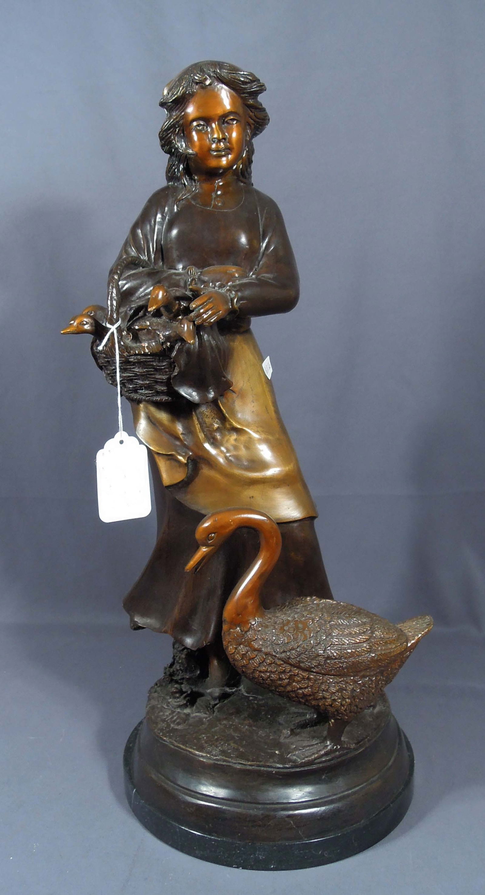 VINTAGE BRONZE SCULPTURE OF YOUNG GIRL WITH DUCKS: A adorable bronze of young girl holding a basket full of young ducklins with mother duck at her feet. Black marble base. 26" high.