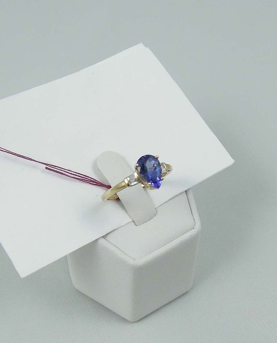 LADIES 10K Y.G., TANZANITE & DIAMOND RING: A highly polished mount set with a very fine pear shaped tanzanite weighing approx. 1 ct. Tanzanite flanked by two baguette cut diamonds totaling approx. .15 ct.