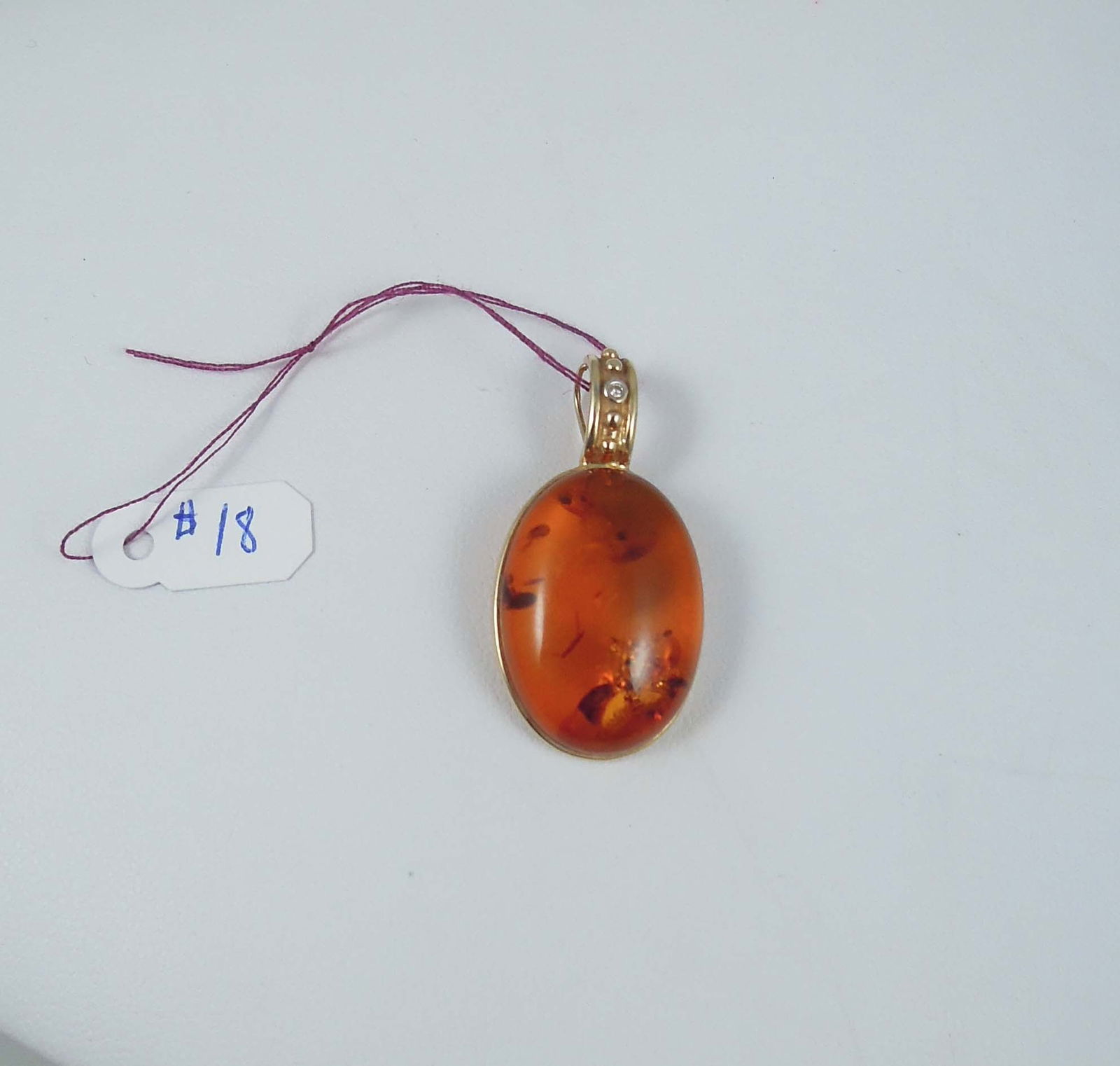 LADIES 14K Y.G., AMBER AND DIAMOND PENDANT: A yellow gold mount with a single full cut round diamond supports a large cabochon amber. Pendant 1 1/2" high, 3/4" wide.