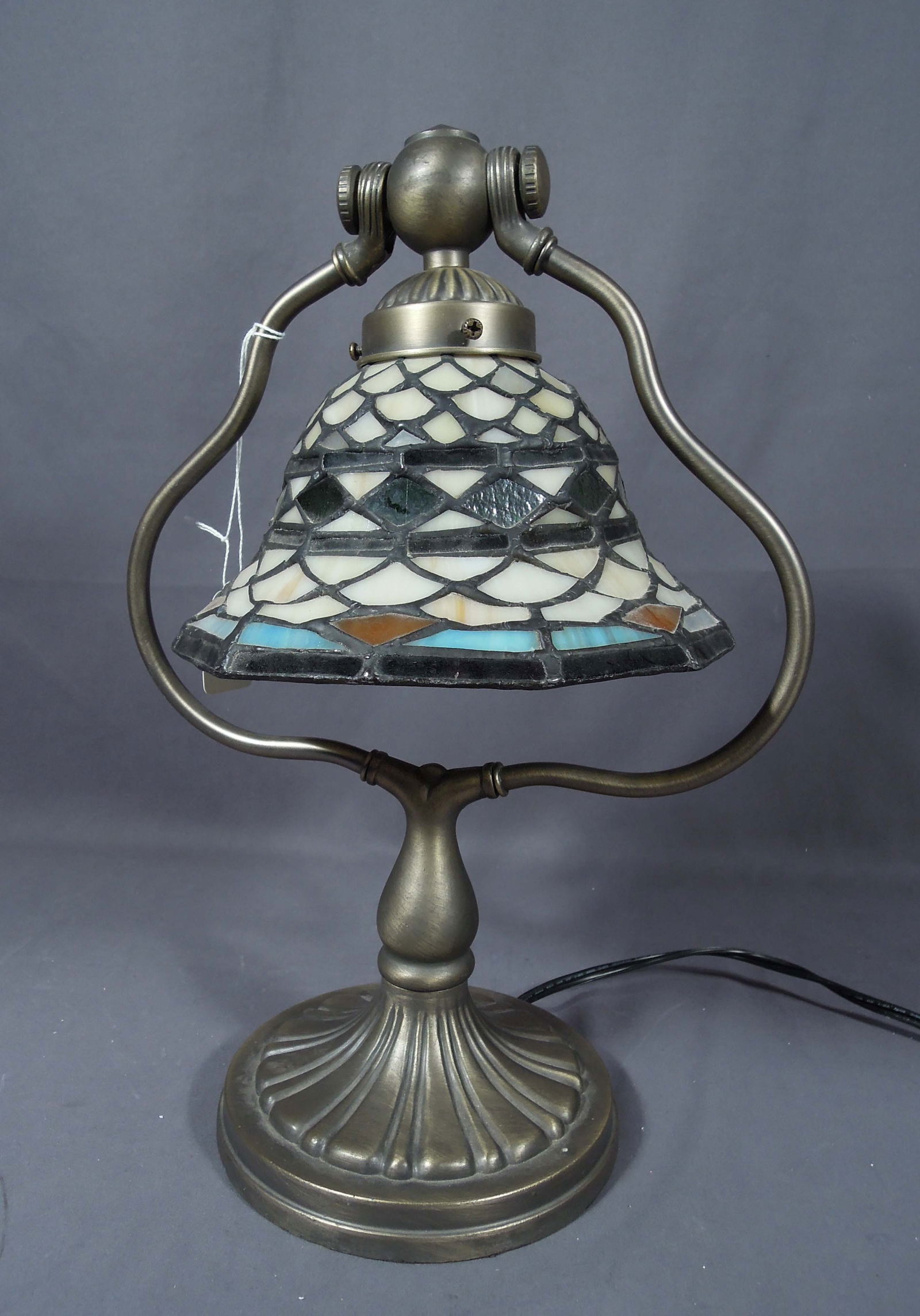 TIFFANY STYLE LEADED GLASS TABLE LAMP: Metal harp base supports a leaded glass bell shaped shade. 15" high, 7 1/2" dia.