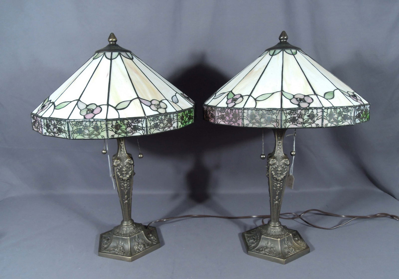 PAIR VINTAGE METAL AND LEADED GLASS TABLE LAMPS: Each ornate Victorian style base supports a Tiffany style leaded glass shade. 22 1/2" high, 16" dia.