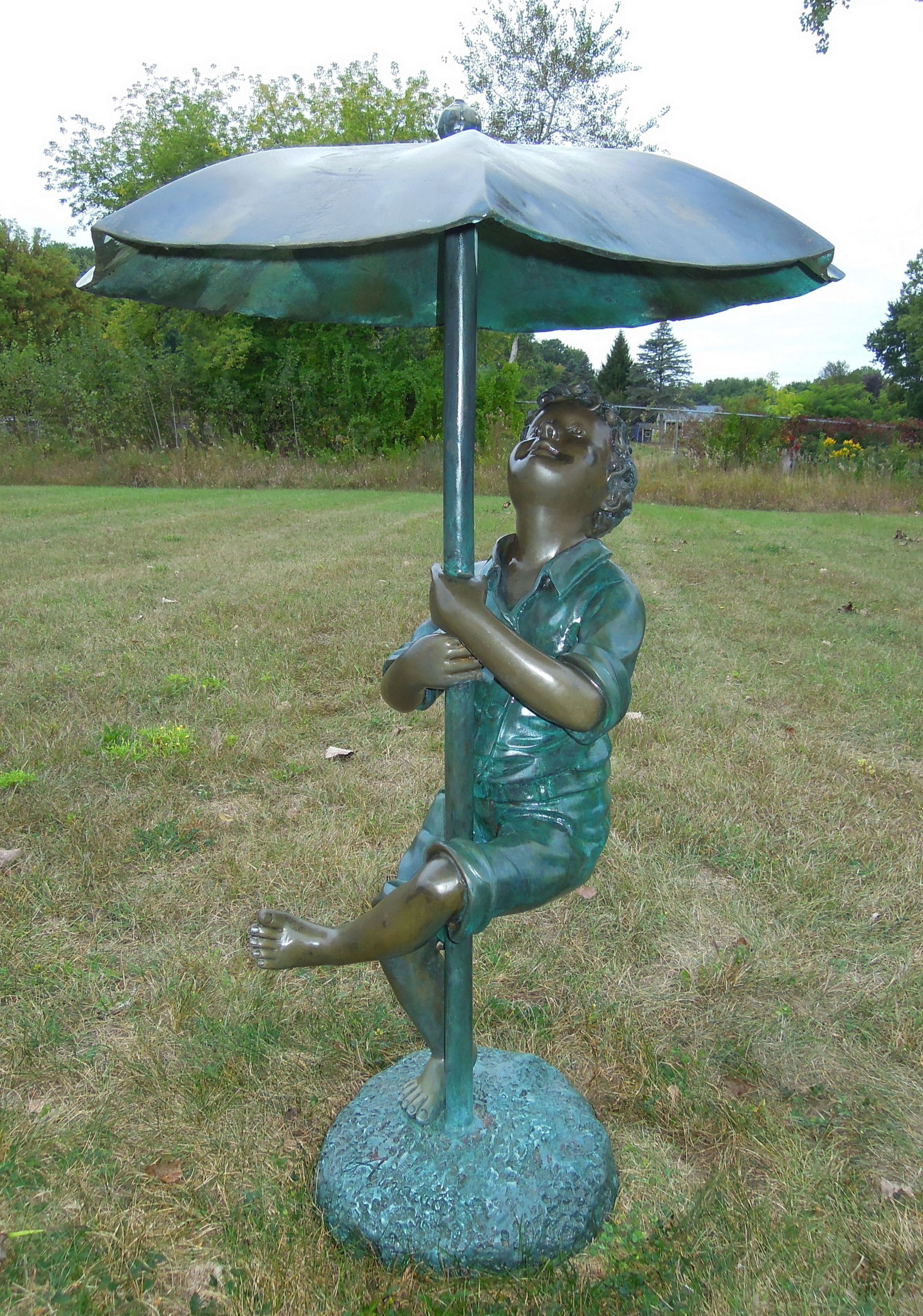 VINTAGE BRONZE SCULPTURE/FOUNTAIN OF YOUNG BOY HOLDING UMBRELLA: Great aged patina. Note: Water emerges from top of umbrella when used as a fountain. Signed. 48" high, 31" dia.