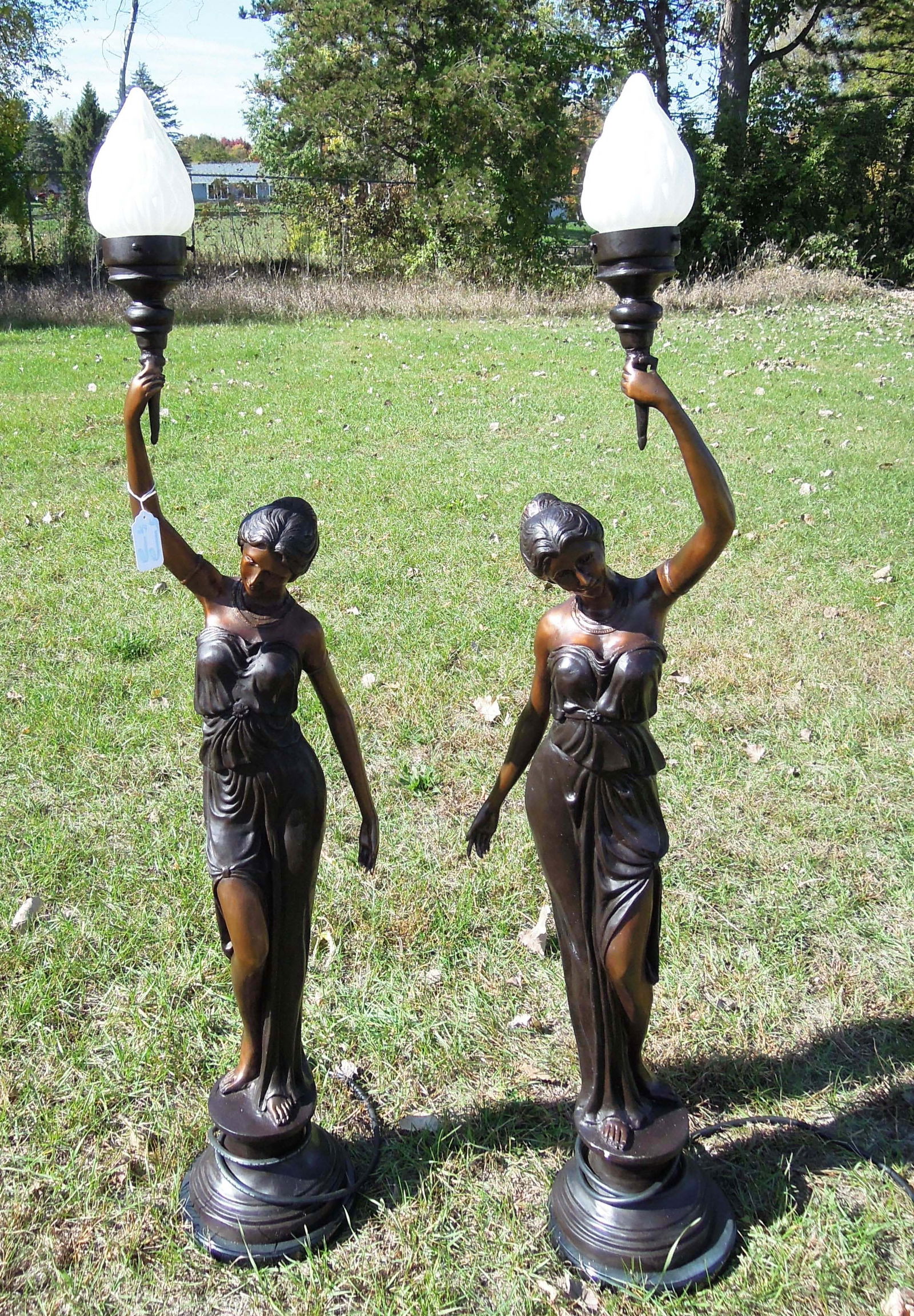 PAIR OF BRONZE FIGURAL TORCHERE LAMPS: Pair of beautiful bronze figural torcheres. Two ladies with out strech arms supporting torch light. Excellent detail, two color patina, black marble base and electrified. 52" high.