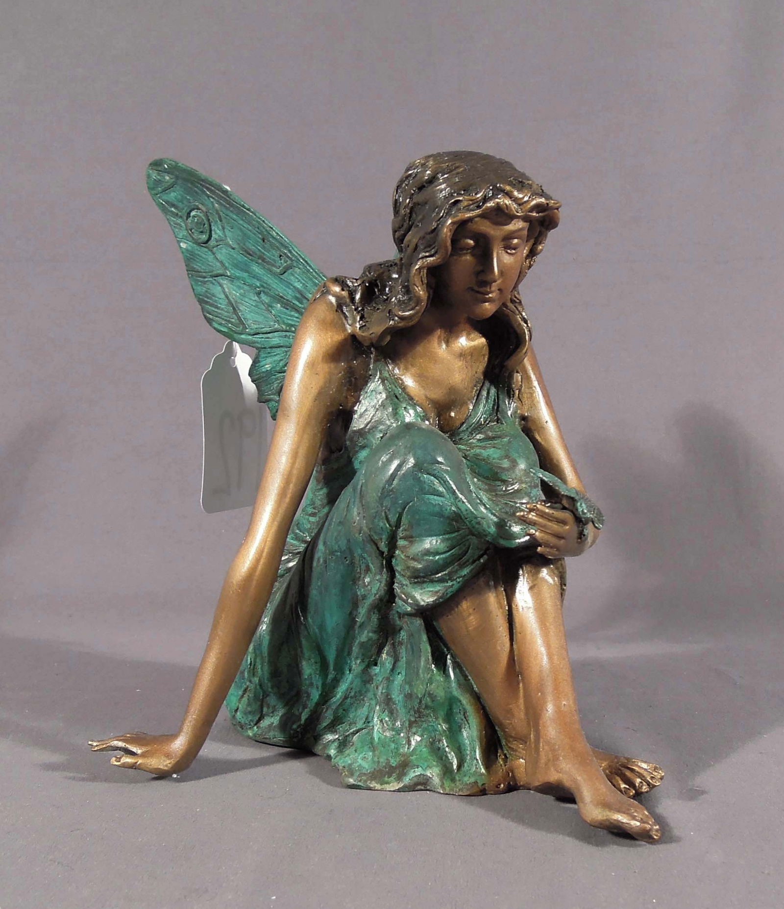 ADORABLE BRONZE SCULPTURE OF SEATED FAIRY WITH BUTTERFLY: Two color patina. 8 1/2" high, 10" wide.
