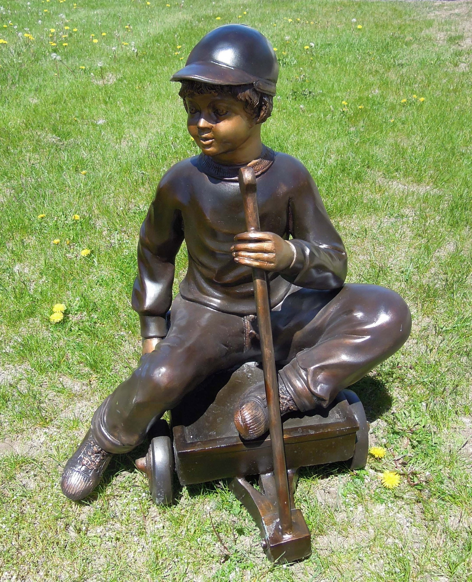 LIFE SIZE BRONZE SCULPTURE OF YOUNG BOY SEATED IN WAGON: Excellent detail. Brown and gold patina. 31" high, 22" wide, 24" deep.