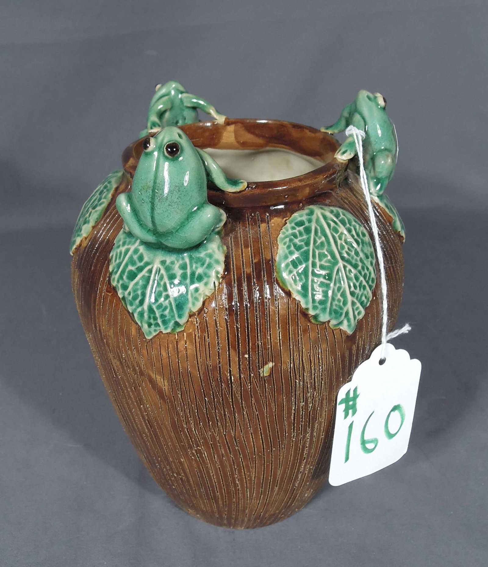 MAJOLICA STYLE FINE POTTERY FROG MOTIF VASE: A ribbed vase with brown and green glazing with three frogs on top portion. 8" high, 6" dia.