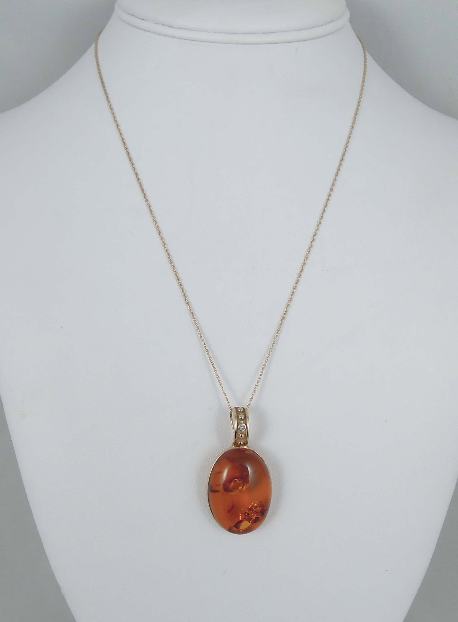 LADIES FINE 14K Y.G., AMBER AND DIAMOND NECKLACE: A yellow gold chain supports a large cabochon amber pendant. Diamond top with a single full cut round diamond.