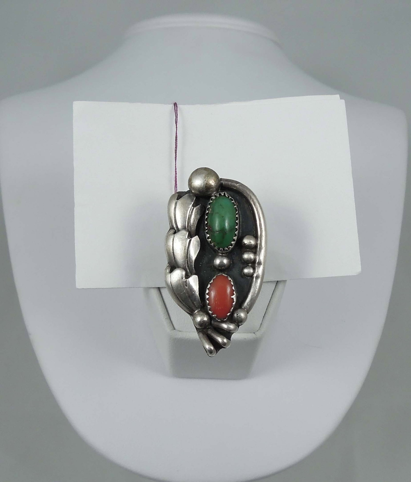 VINTAGE NATIVE AMERICAN STERLING SILVER, GREEN TURQUOISE AND CORAL RING: An elaborate sterling silver ring set with an oval cabochon green turquoise and coral. 12.2 grams.