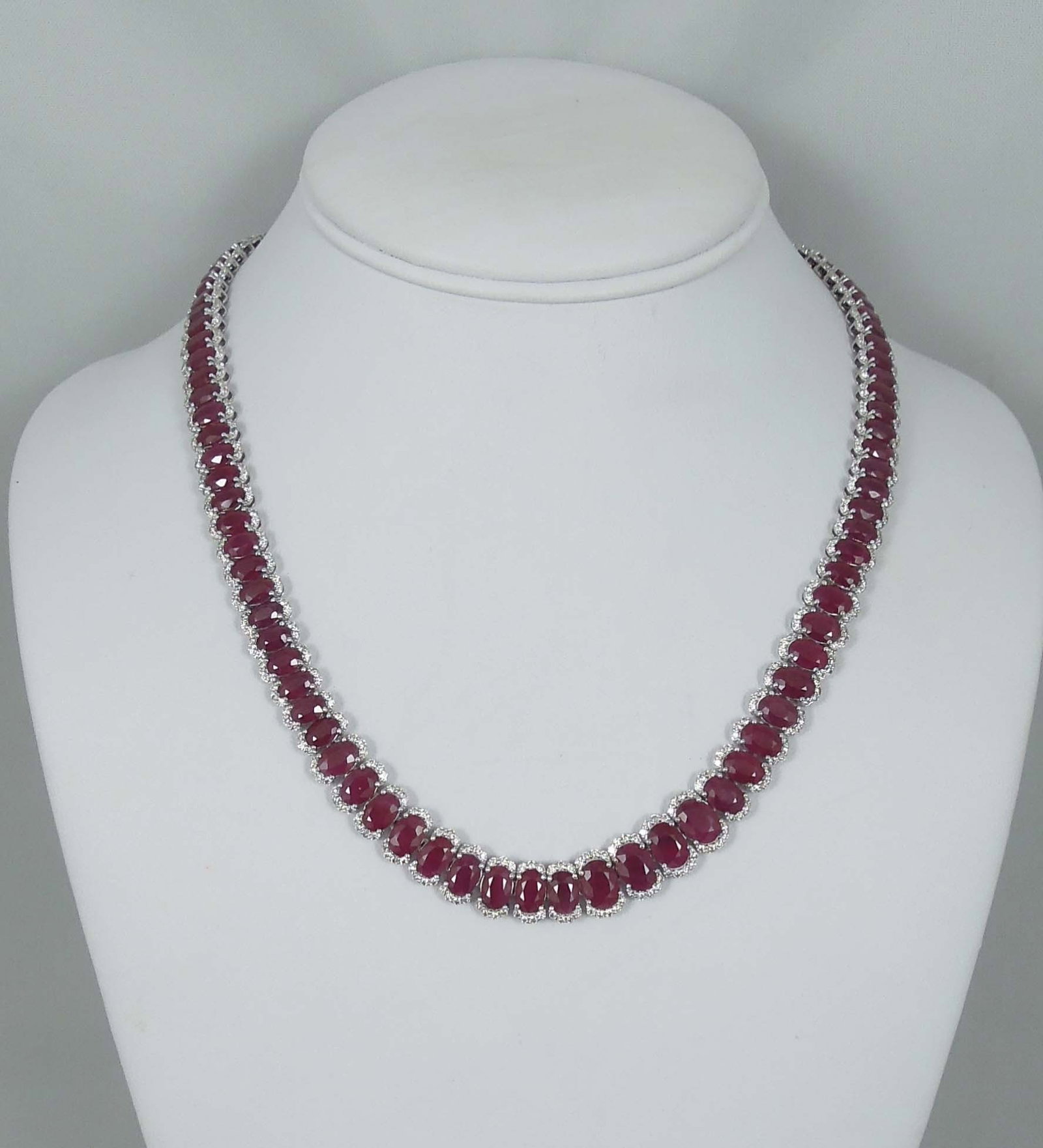 SPECTACULAR LADIES OSCAR FREIDMAN PLATINUM, BURMESE RUBY & DIAMOND ETERNITY NECKLACE: A platinum necklace set with 98 beautiful oval shaped Burmese rubies weighing approx. 60.69 cts. Each ruby surrounded by a single row of full cut round diamonds totaling approx. 6.03 cts. Necklace 18"