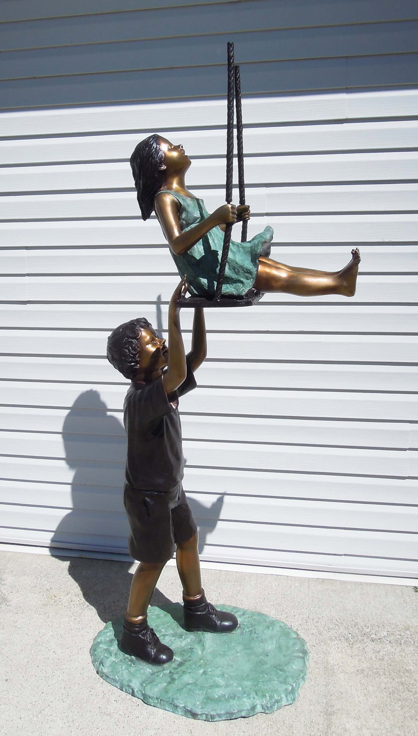 SPECTACULAR LIFE SIZE BRONZE SCULPTURE OF KIDS PLAYING ON SWING: A young boy pushes young girl on swing. Excellent detail. Three color patina. 76" high, 21" wide, 31" deep.