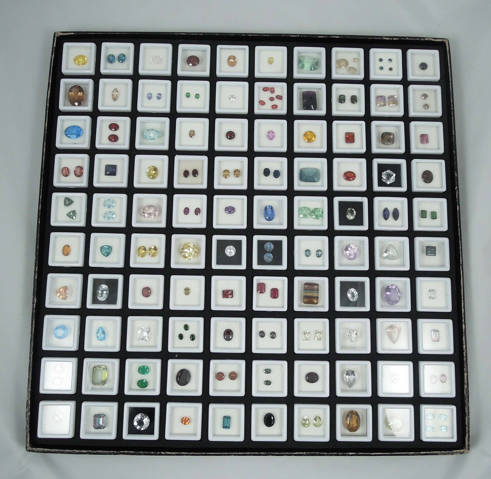 LARGE CASED GROUP OF MANY NATURAL GEMSTONES: Includes blue topaz, citrine, emerald, amethyst, florite, sapphire, labadorite and more. 100's of cts. Case 14 1/2" sq.