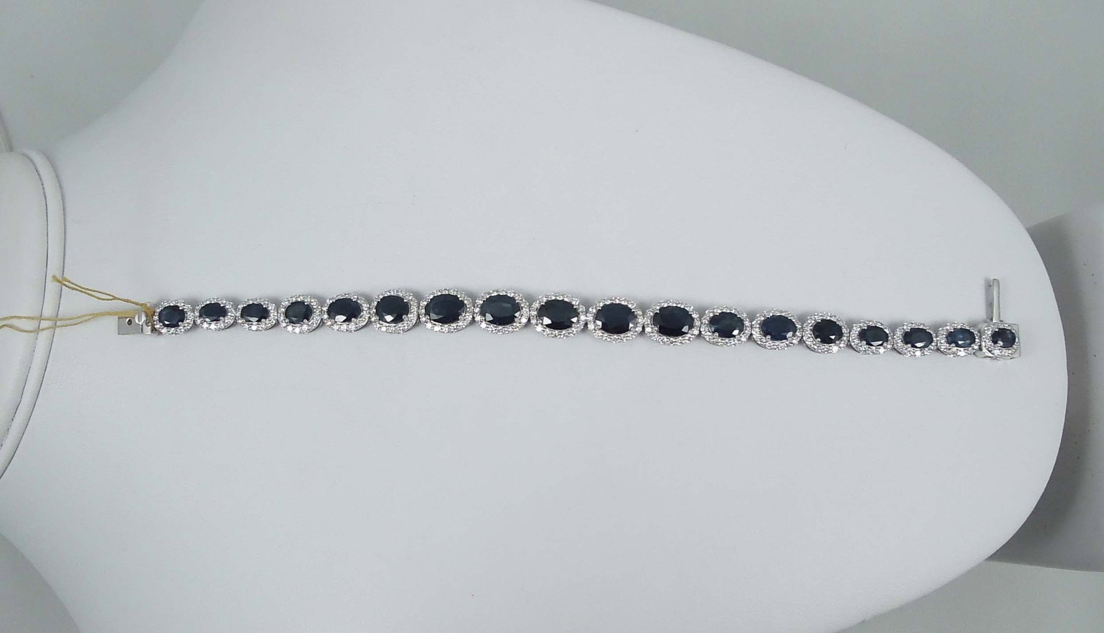 LADIES FINE PLATINUM, SAPPHIRE & DIAMOND ETERNITY BRACELET: A straight row platinum bracelet set with multiple oval links set with fine oval cut blue sapphires. Each sapphire surrounded by a single row of full cut round diamonds. Total sapphire weight approx. 