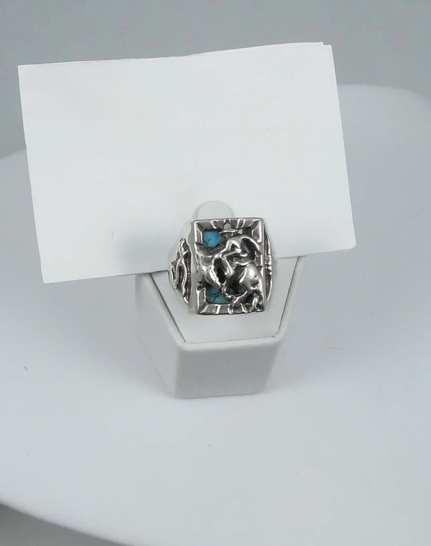 GENTLEMEN'S VINTAGE NATIVE AMERICAN STERLING SILVER & TURQUOISE RING: A large sterling silver ring supports a center turquoise with bronco buster in high relief..