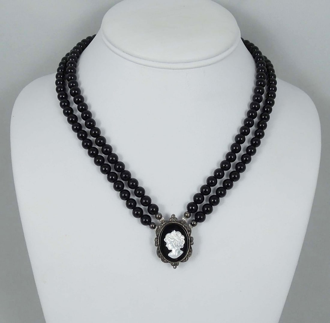 LADIES VINTAGE ONYX AND CAMEO NECKLACE: A double strand of onyx beads supports a vintage sterling silver pendant set with a mother-of-pearl cameo.