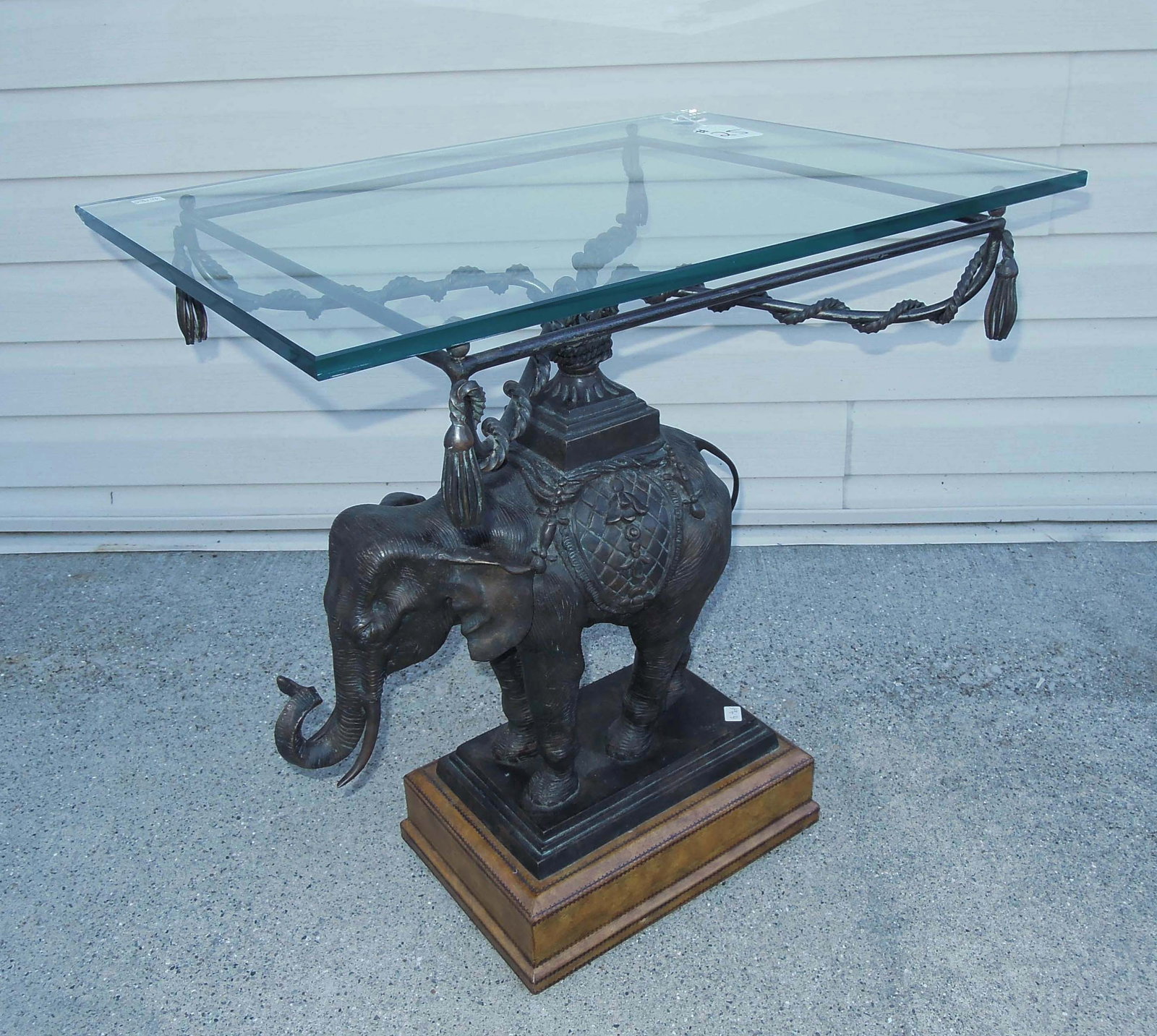 DESIGNER MAITLAND-SMITH WOOD & BRONZE ELEPHANT MOTIF TABLE: A tiered wood & tooled leather base with standing elephant which supports a thick glass top (small chip on edge of glass top). Original Maitland-Smith sticker on base. 25 1/2" high, 24" wide, 18"