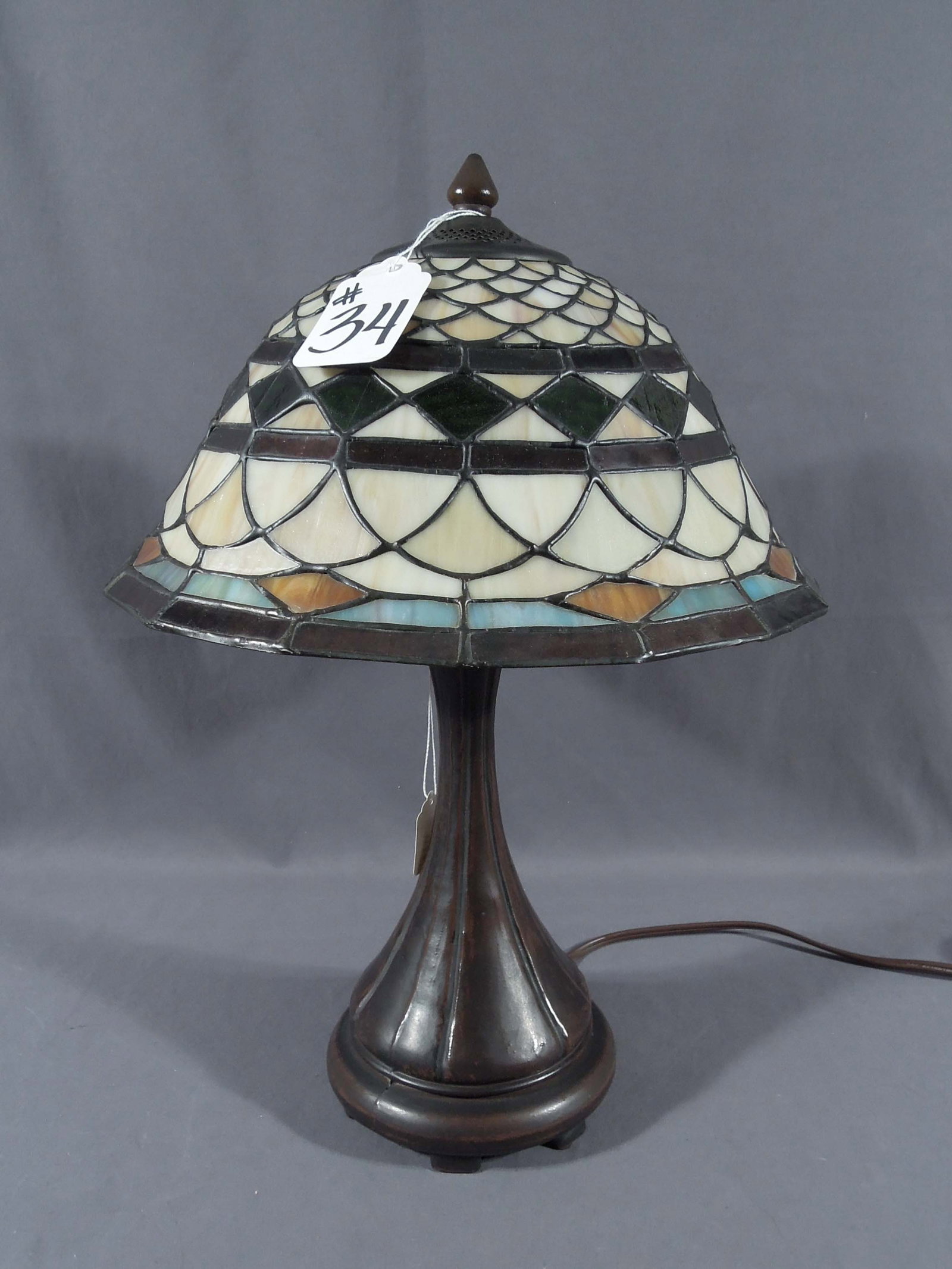 BEAUTIFUL TIFFANY STYLE METAL AND LEADED GLASS TABLE LAMP: A metal base supports a domed shade with geometric design. Excellent condition. 18 1/2" high, 13" dia.