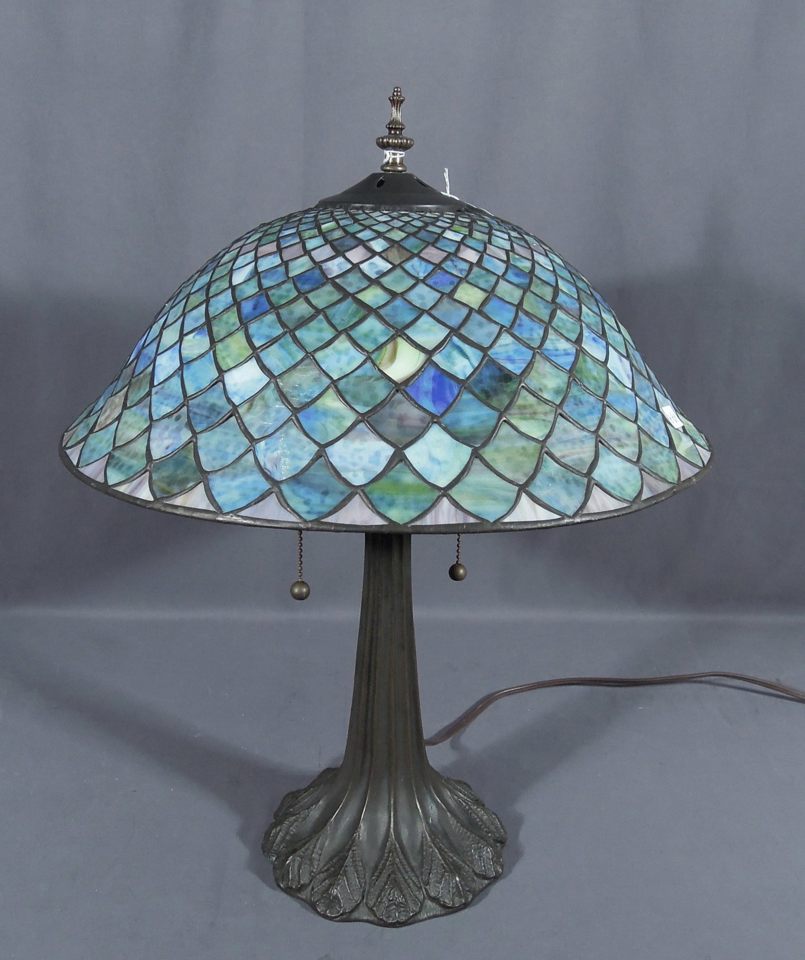 VINTAGE METAL AND LEADED GLASS TABLE LAMP: A peacock feather motif base supports a beautiful multi-colored dome leaded glass shade. Excellent condition. 22" high, 17 1/2" dia.
