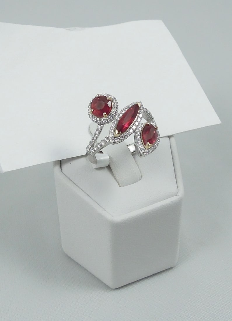 LADIES VERY FINE PLATINUM & 18K W.G., RUBY & DIAMOND RING: A modern style ring supports three natural unheated rubies (two oval cut & one marquise cut rubies).Total ruby weight approx. 3.06 cts. Ring completed with fine full cut round diamonds totaling