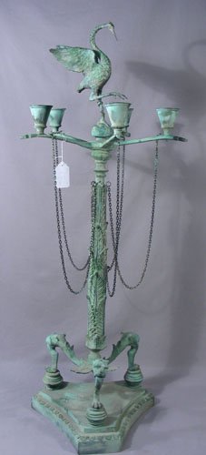 PAIR VERY UNUSUAL BRONZE FLOOR CANDELABRA: A triangular base with lion's heads and claw feet support an ornate column supporting a five light candelabra with a tall bird finial. Green coloration. 46" high, 17" dia.