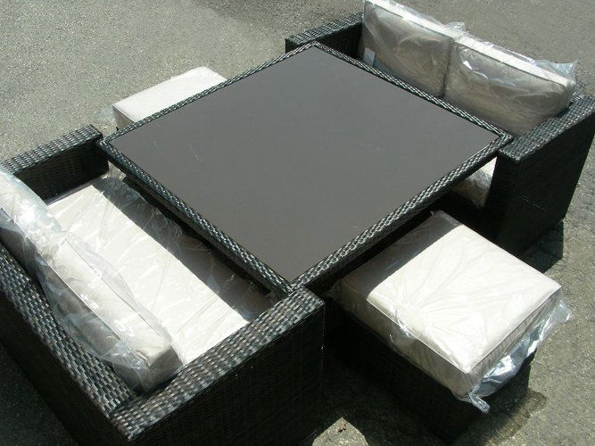 FIVE PIECE OUTDOOR PATIO SET: Set consists of: Square table with glass top, two settees and two side seats. Tan cushions. Weather proof. Table 28 3/4" high. 48 1/2" wide, 53" long.