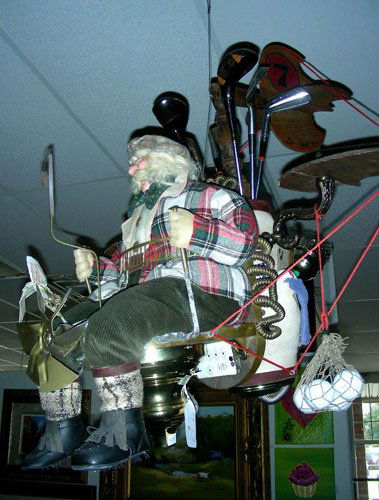 CUSTOM MADE HANGING GOLF SCULPTURE: Sculpture of an old man driving a flying golf cart made from golf clubs, lamp parts, fans, car mirrors and other objects. Made by Brian Kidwell and dated 1995. 32" high.