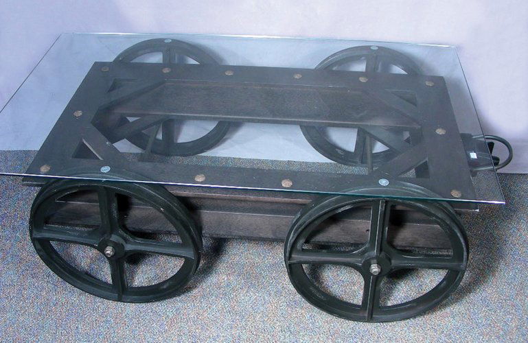 REPRODUCTION MERCANTILE COCKTAIL TABLE WITH GLASS TOP: Table looks like an old wagon with rectangular glass top. 18" high, 49" wide, 28" deep.