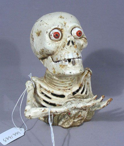 VINTAGE HEAVY CAST IRON SKELETON BANK: When side lever is push, hand goes to mouth to insert coin. Also eye balls pop out. 6 1/2" high.