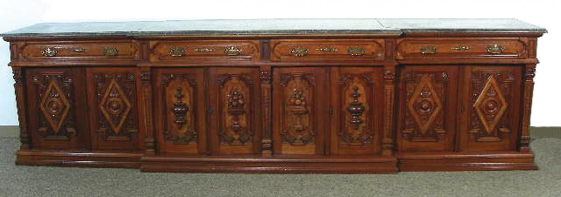 SPECTACULAR ANTIQUE HAND CARVED WOOD SIDEBOARD: A 12' long sideboard with eight heavily carved doors which open to reveal storage and four carved drawers. Very ornate. Sideboard complete with a three section marble top. This is a very fine and heav
