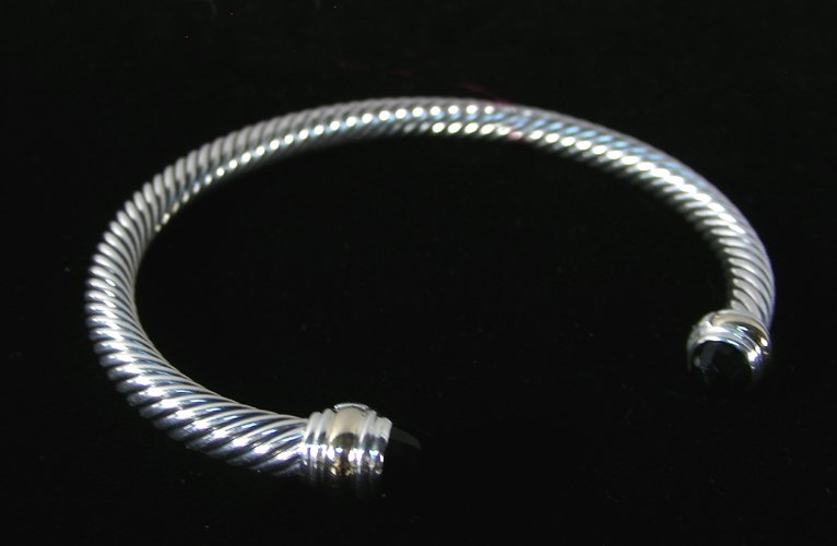 DESIGNER DAVID YURMAN STERLING SILVER & 14K & ONYX: A heavy sterling silver cable bracelet set with two faceted onyx with two rows of 14K yellow gold. Signed.