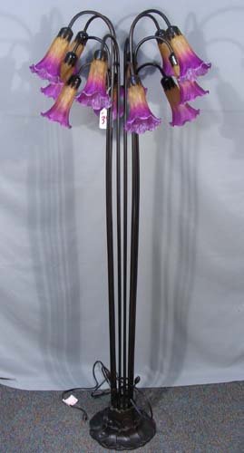 METAL AND ART GLASS LILY FLOOR LAMP: A tall metal floor lamp with 12 arms which terminate to art glass lily shades in gold and maroon coloration. 61 1/2" high.