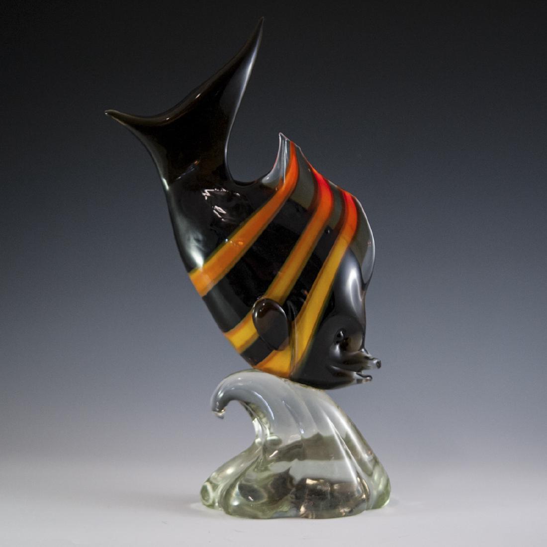 Murano Glass Fish: DESCRIPTION: A Murano glass fish embellished with an overall ebony hue garnished with yellow and amber hued stripes along its body. Fitted to a clear glass, ridged, wave motif base. CIRCA: 20th Ct. OR
