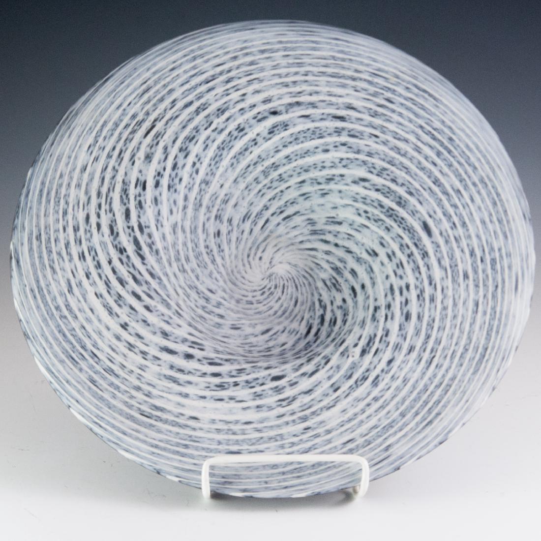 Murano Glass Style Charger: DESCRIPTION: A Murano glass style charger. Features a frosted glass surface with interior swirled hues. Finished with a black hued, satin texture along the underside, and a scalloped center. CIRCA: 20