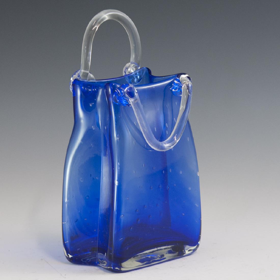 Vintage Cobalt Glass Purse Vase: DESCRIPTION: A vintage cobalt glass vase in the motif of a purse with a handle arching upwards, and the other down along the side. Finished with interior controlled bubble accents. CIRCA: Mid-Late 20t