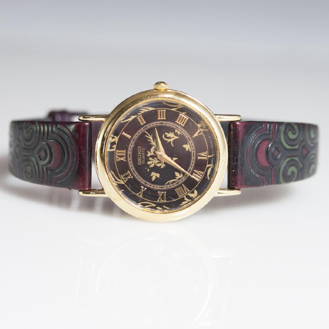 Vintage Ladies Seiko Watch: DESCRIPTION: A vintage ladies seiko watch. Features a genuine leather band engraved with floral motifs and scrolled accents. finished with a gilded case with floral motifs enveloped by roman numeral d