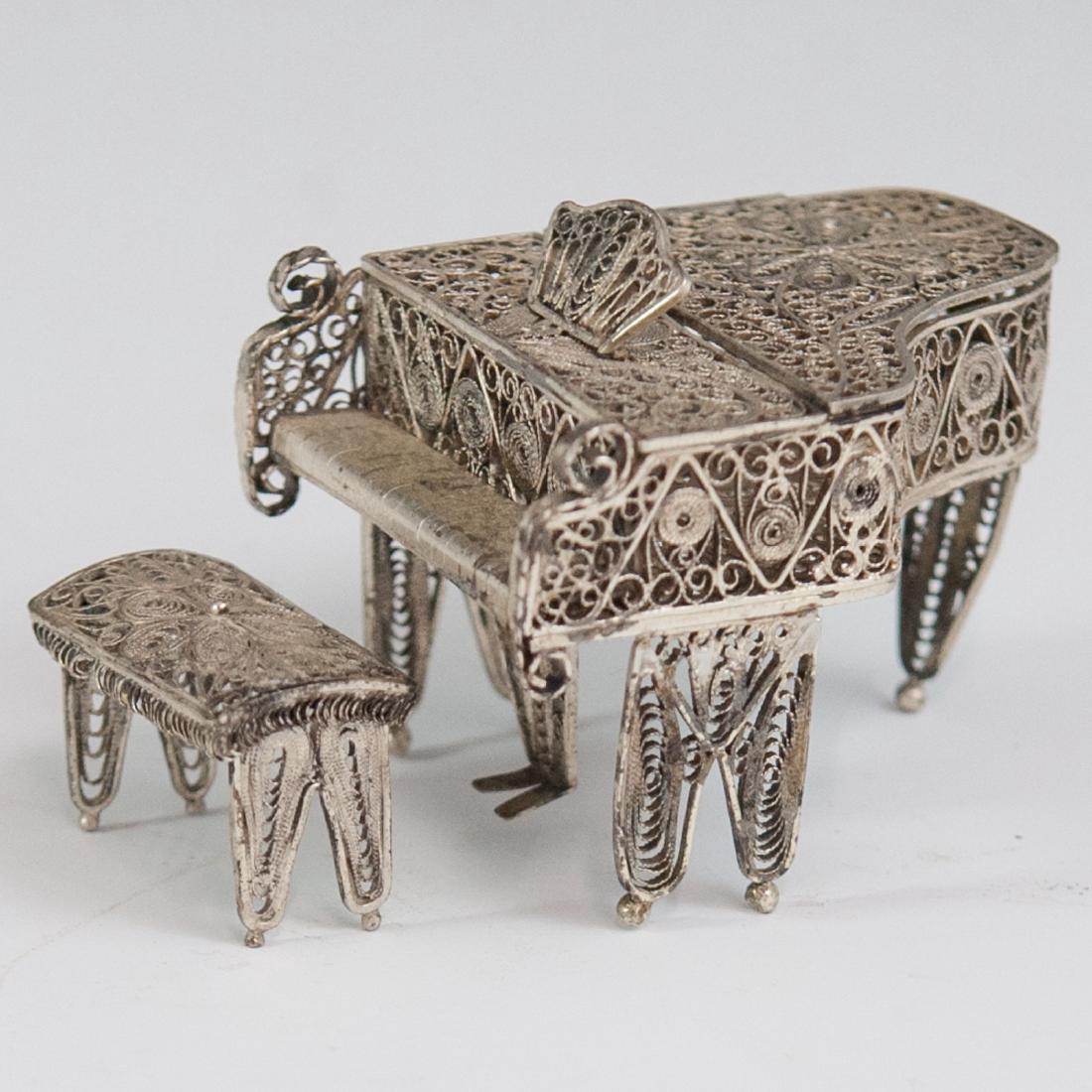 Continental 800. Silver Filigree Piano: DESCRIPTION: An antique, diminutive, .800 silver piano. Comprises of a piano and a bench garnished with filigree floral motifs and open work designs. Finished with a hinge that opens a crevice along t