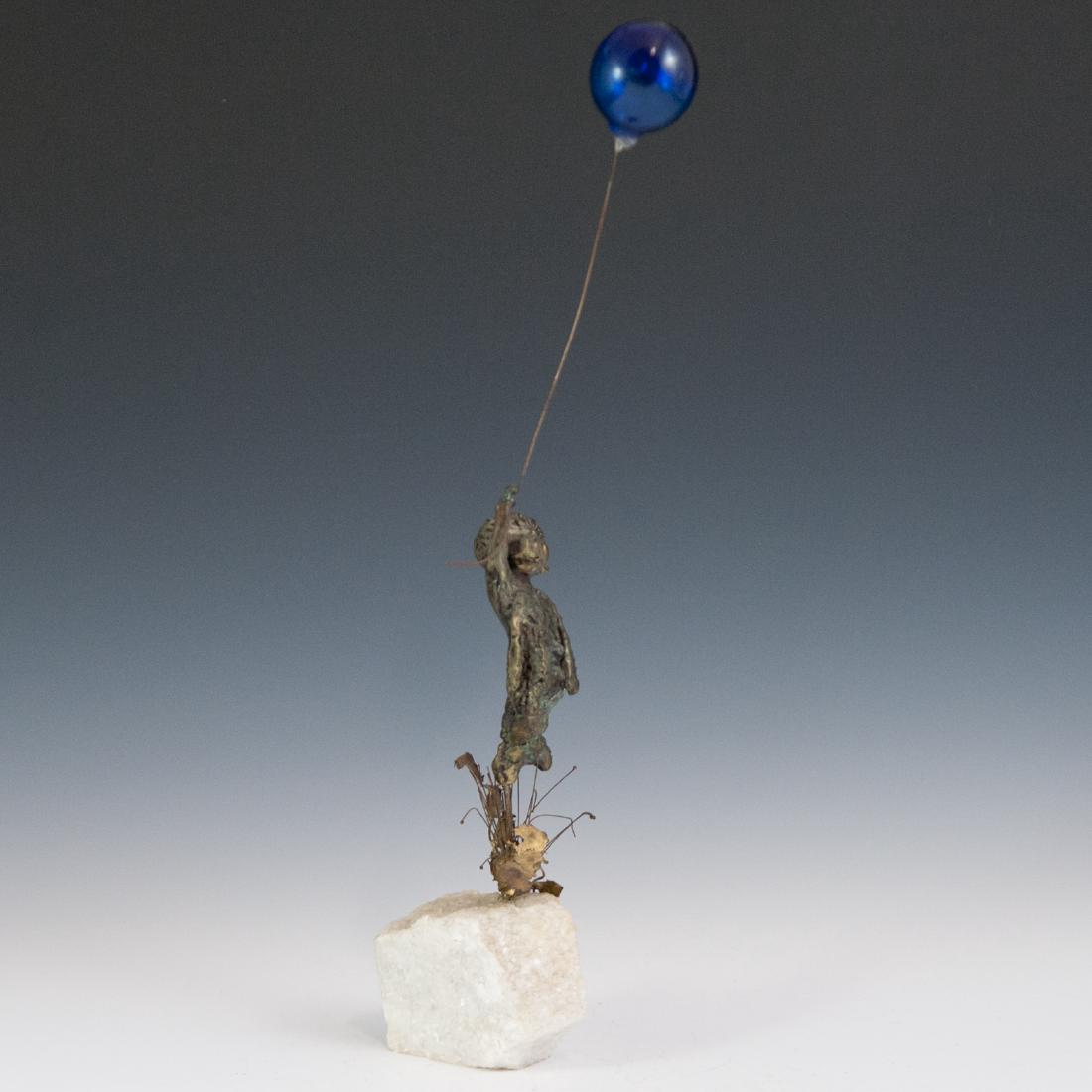 After Malcolm Moran (American 1923-2011): DESCRIPTION: A bronze sculpture in the manner of Malcolm Moran. Features a young boy soaring above plants fitted to a rough quartz boulder grasping a cobalt blue glass balloon above him. Unsigned. CIR