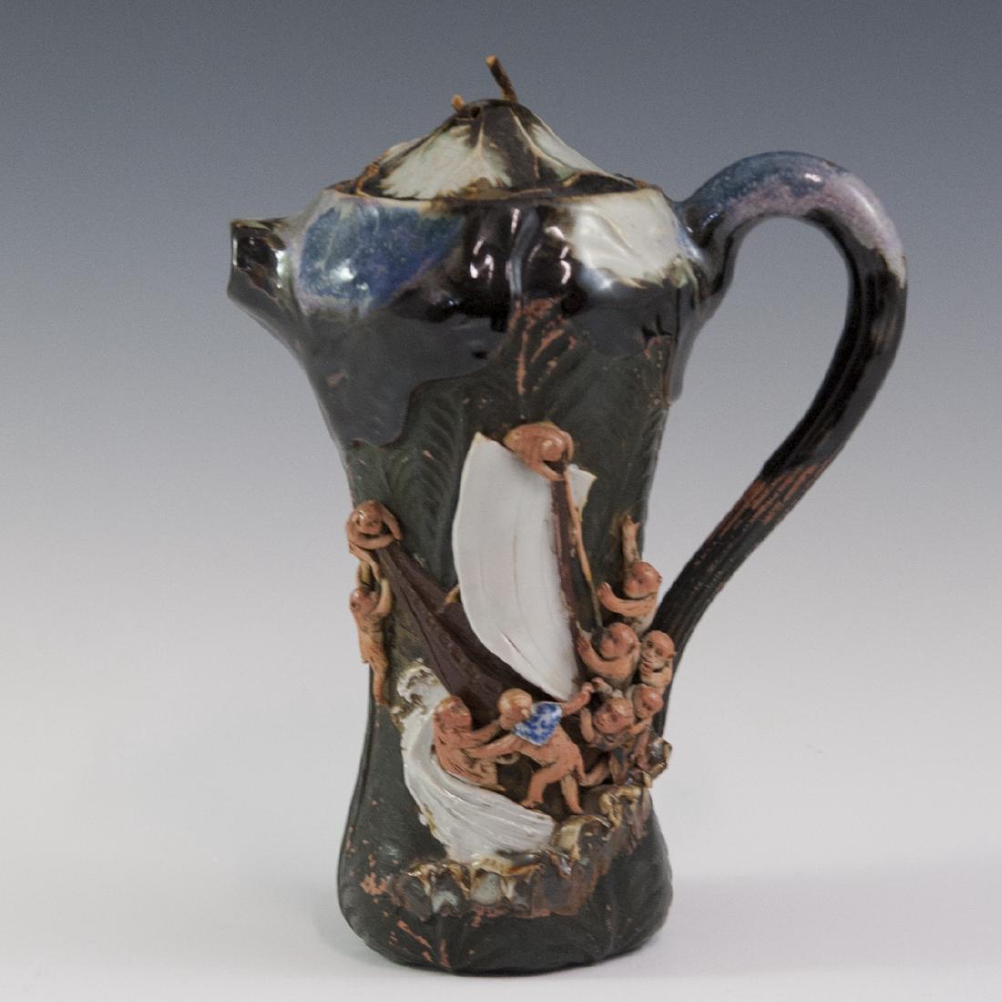 Glazed Pottery Teapot: DESCRIPTION: A glazed pottery teapot featuring an overall floral motif as well as monkeys attempting to salvage a sinking ship along the side. Marked with an AA mark, unidentifiable. CIRCA: Mid-Late 2