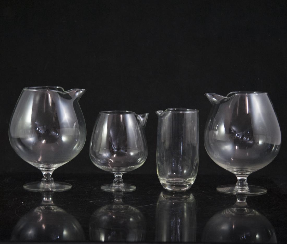 Assorted Crystal Pitchers: DESCRIPTION: A set of crystal pitchers comprising of a pair of large, bulbous formed pitchers, a cylindrical beaker with a folded spout, and a cognac glass form pitcher with a folded spout. CIRCA: Mid