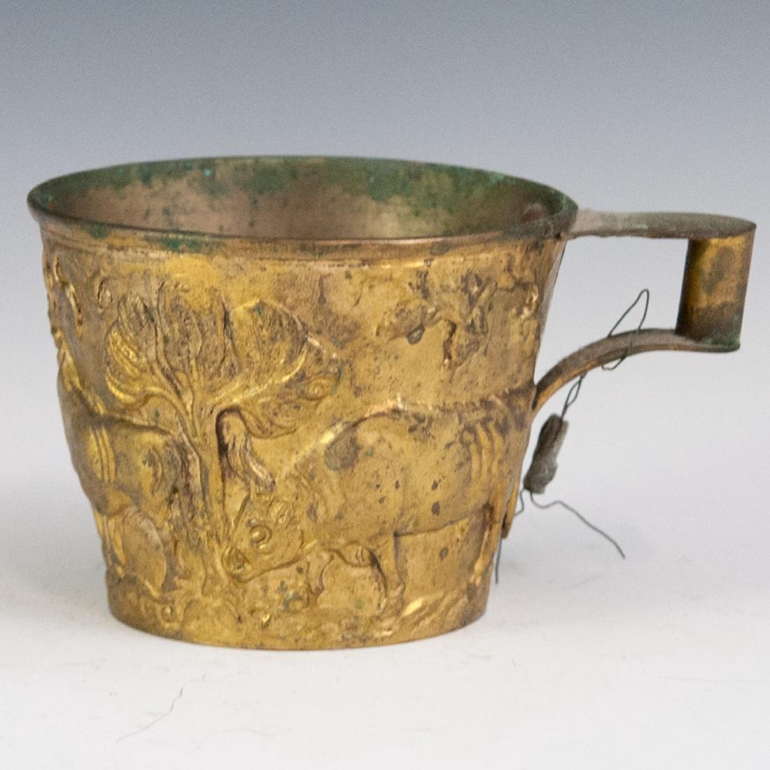 Vintage Greek Brass Relief Goblet: DESCRIPTION: A vintage Greek brass cup. Features embossed Neoclassical scenes of a herder leading a herd of bulls, backed by tree motifs. Marked:"Made in Greece". CIRCA: Mid-Late 20th Ct. ORIGIN: Gree