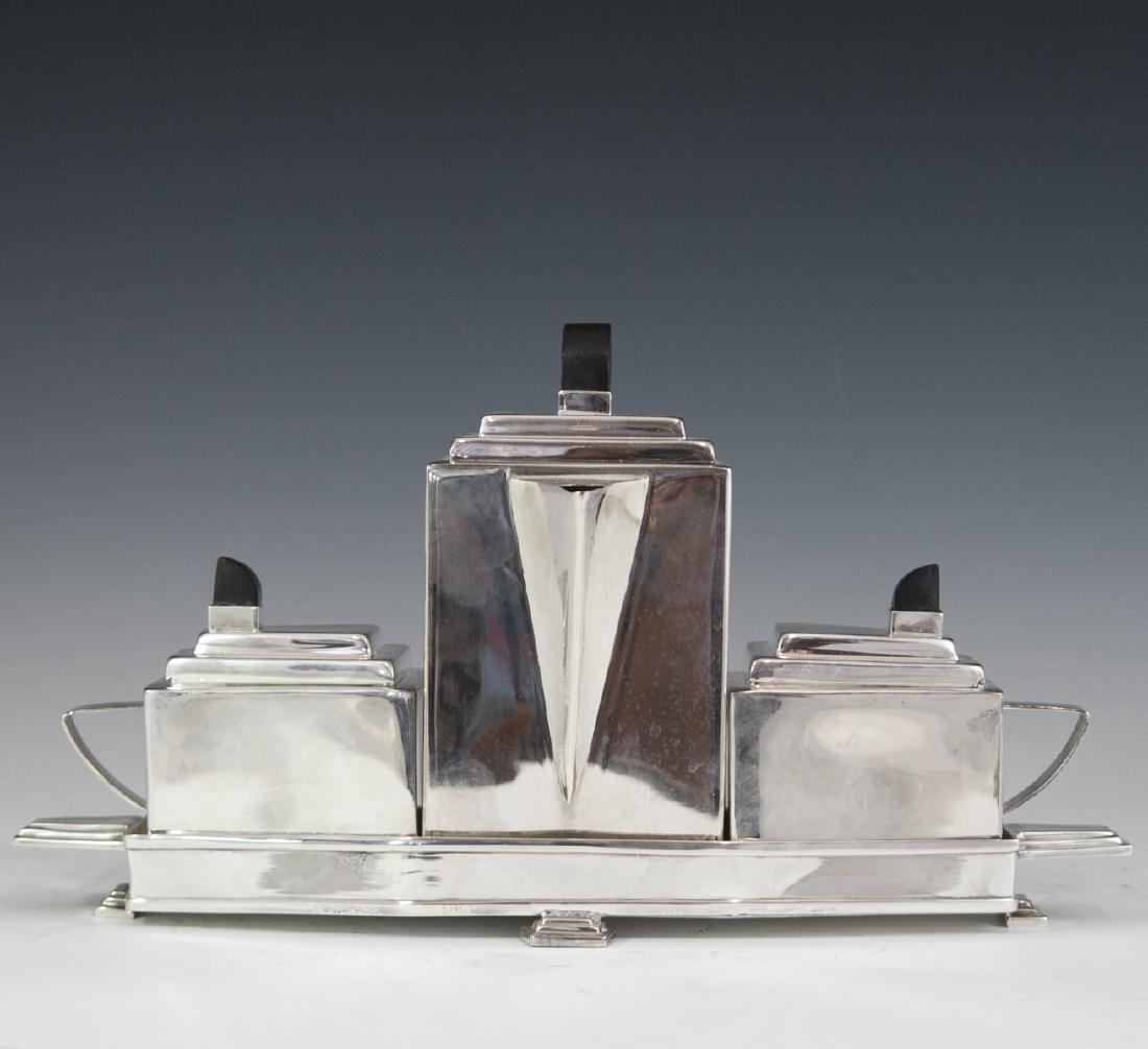 Art Deco Silver Plated Tea Set: DESCRIPTION: An Art Deco, silverplated tea set. Comprises of a an elongated, octagon base tray with a tea urn, sugar cellar, and tea pot fitting snug in the tray when placed together. Each are embelli