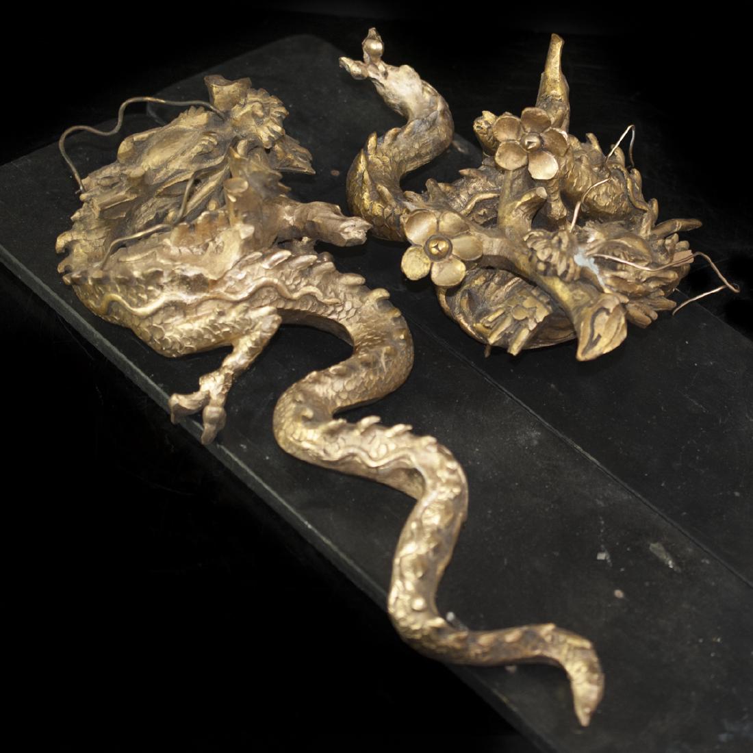 Pair of Gilded Wood Dragons: DESCRIPTION:Pair of elegantly hand carved fierce wood dragons holding tree branches in their mouths with floral garnishment. Remarkable detailing seen in the face and individual scales. Finished in a 
