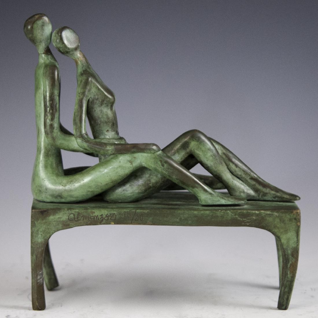 Jose J "Shalom" Almanzor (Mexican b. 1962): DESCRIPTION: A contemporary bronze sculpture by Mexican artist, Jose J "Shalom" Almanzor. Features a man and woman laying down embracing one another while seated atop a table with arching legs. Finish